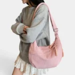 Sac Banane XXL Femme Velours Côtelé Sac banane XXL en velours côtelé rose poudré porté en bandoulière par une femme au style casual chic