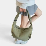 Sac Banane XXL Femme Velours Côtelé Sac banane XXL en velours côtelé vert kaki tenu à la main par une femme au style preppy
