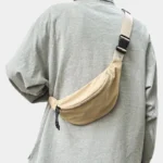 Sac Banane Nylon Satiné Léger Sac banane nylon satiné beige porté en bandoulière ramené dans le dos avec boucle clip noire