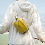 Sac Banane Bicolore Randonnée Nylon Léger Homme de dos portant un sac banane bicolore jaune et crème basculé dans le dos, sangle en bandoulière.