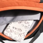 Sac Banane Bicolore Randonnée Nylon Léger Intérieur d'un sac banane orange ouvert, doublure grise et compartiment intérieur contenant un téléphone.