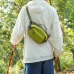 Sac Banane Bicolore Randonnée Nylon Léger Homme de dos portant un sac banane bicolore vert anis basculé dans le dos, sangle en bandoulière.