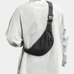 Sac Banane Nylon Satiné Léger Sac banane nylon satiné noir porté en bandoulière ramené dans le dos avec boucle clip assortie