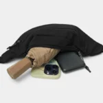 Sac Banane Nylon Satiné Léger Sac banane nylon satiné noir ouvert laissant dépasser un parapluie pliant et un téléphone
