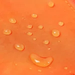 Sac banane orange en nylon oxford en gros plan sur des gouttes d'eau perlant à la surface