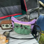 Sac Banane Randonnée Ultraléger Double Sangle Sac banane violet et vert posé de trois quarts sur une table de camping en extérieur