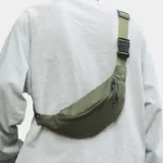 Sac Banane Nylon Satiné Léger Sac banane nylon satiné vert kaki porté en bandoulière ramené dans le dos avec boucle clip noire