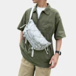 Grand Sac Banane Randonnée Dos Rembourré Sac banane en nylon ripstop gris clair porté en bandoulière sur la poitrine par un homme de face