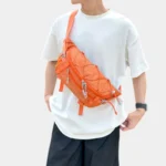 Grand Sac Banane Randonnée Dos Rembourré Sac banane en nylon ripstop orange porté en bandoulière sur la poitrine par un homme de face