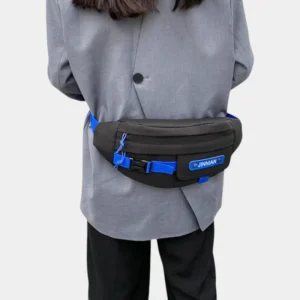 Sac banane techwear en nylon noir porté à la taille dans le dos par une femme avec poche à rabat