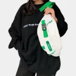 Sac banane techwear en nylon blanc porté en bandoulière sur la poitrine par une femme de face