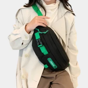 Sac banane techwear en nylon noir porté en bandoulière sur la poitrine par une femme de face