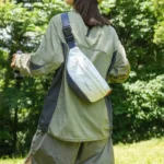 Sac Banane Coupe-Vent Années 90 Déperlant Sac banane coupe-vent années 90 blanc porté en bandoulière dans le dos par une femme lors d'une balade en forêt