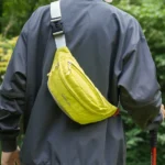 Sac Banane Coupe-Vent Années 90 Déperlant Sac banane coupe-vent années 90 jaune fluo porté en bandoulière dans le dos par un homme en randonnée