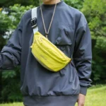 Sac Banane Coupe-Vent Années 90 Déperlant Sac banane coupe-vent années 90 jaune fluo porté en bandoulière par un homme de face lors d'une balade en forêt