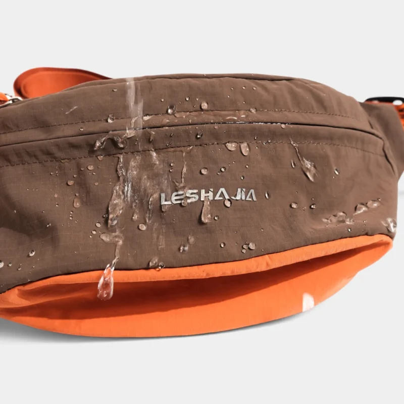 Gros plan sur le nylon ripstop déperlant du sac banane coupe-vent années 90 marron où perlent des gouttes d'eau
