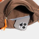 Sac Banane Coupe-Vent Années 90 Déperlant Sac banane coupe-vent années 90 marron vu de près, poche zippée ouverte sur un smartphone glissé à l'intérieur