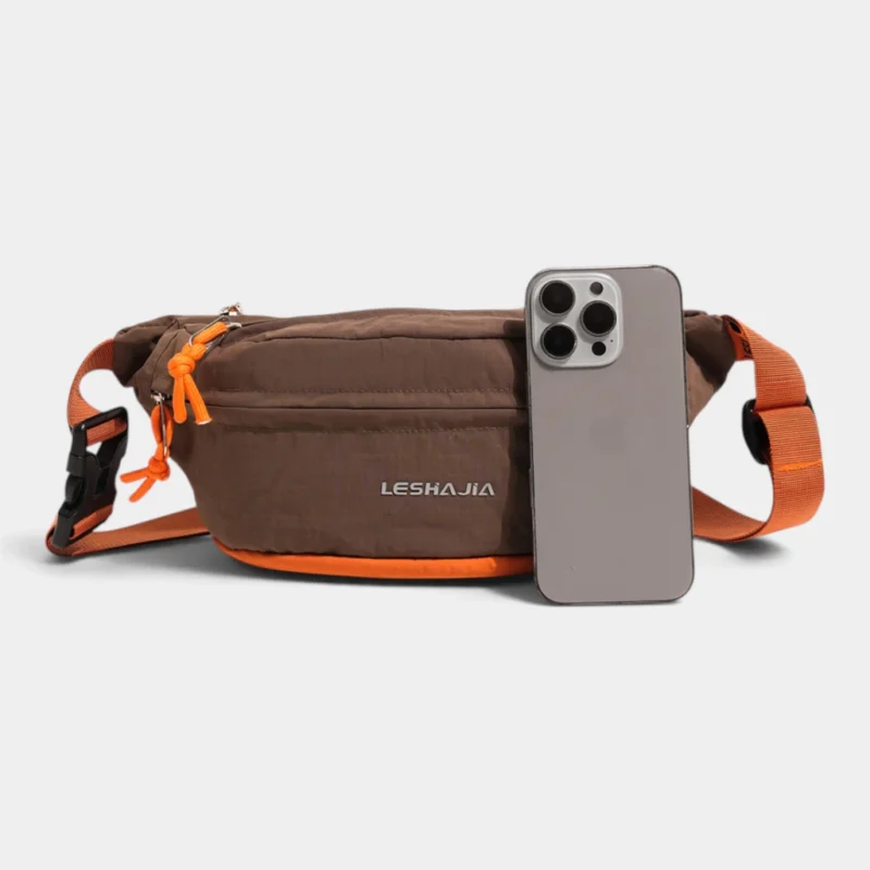Sac banane coupe-vent années 90 marron posé de face à côté d'un smartphone qui donne l'échelle de son format