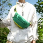 Sac Banane Coupe-Vent Années 90 Déperlant Sac banane coupe-vent années 90 vert émeraude porté en bandoulière sur la poitrine par un homme