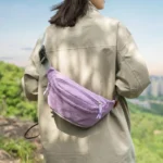 Sac Banane Coupe-Vent Années 90 Déperlant Sac banane coupe-vent années 90 violet lilas porté en bandoulière dans le dos par une femme sur un sentier
