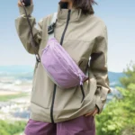Sac Banane Coupe-Vent Années 90 Déperlant Sac banane coupe-vent années 90 violet lilas porté en bandoulière par une femme lors d'une balade en montagne