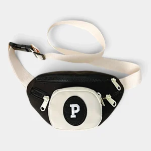 Sac banane enfant noir et crème posé à plat de face avec poche avant crème et lettre P brodée