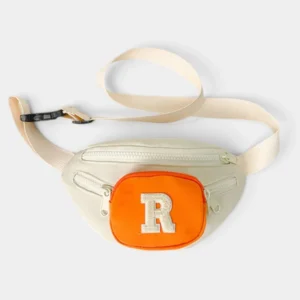 Sac banane enfant crème posé à plat de face avec poche avant orange et lettre R en bouclette