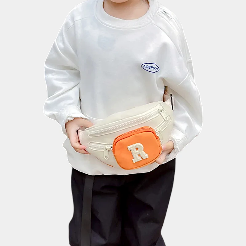 Sac banane enfant crème à poche avant orange porté à la taille par un enfant de face