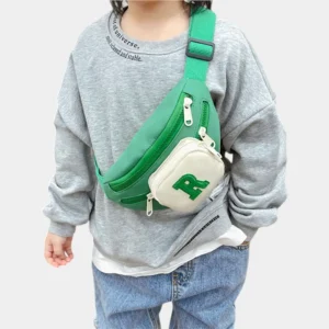 Sac banane enfant vert à poche avant crème porté en bandoulière sur la poitrine par un enfant