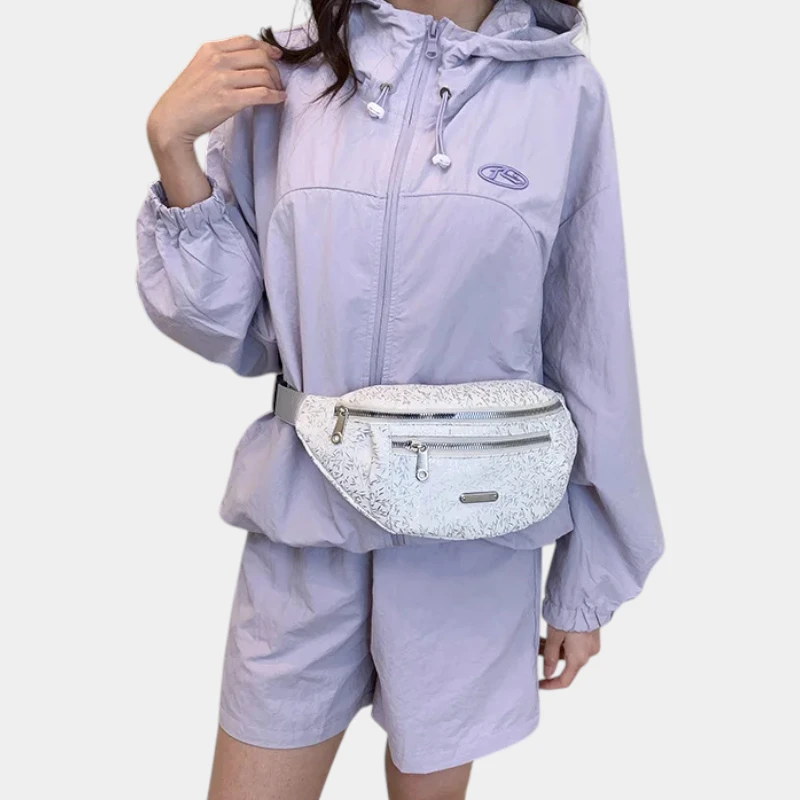 Sac banane demi-lune blanc aux reflets nacrés porté à la taille par une femme vue de face