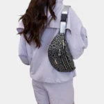 Sac Banane Imprimé Japonais Feuilles Argentées Sac banane demi-lune noir porté en bandoulière dans le dos par une femme vue de dos