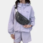 Sac Banane Imprimé Japonais Feuilles Argentées Sac banane demi-lune noir porté en bandoulière sur la poitrine par une femme de face