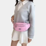 Sac Banane Imprimé Japonais Feuilles Argentées Sac banane demi-lune rose bonbon porté à la taille par une femme de trois-quarts au style preppy