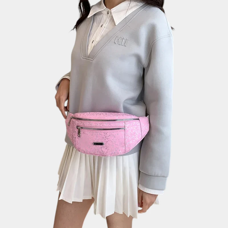 Sac banane demi-lune rose bonbon porté à la taille par une femme de trois-quarts au style preppy