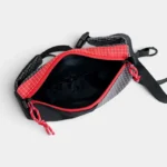 Sac Banane Rectangulaire Allongé Nylon Ripstop Déperlant Sac banane en nylon ripstop noir ouvert sur sa poche principale, doublure noire et fermeture rouge vue de dessus.