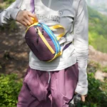 Sac banane en nylon froissé violet porté en bandoulière sur la poitrine par une femme sur un sentier