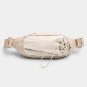 Sac banane en nylon beige de face avec poche avant ton sur ton serrée par un cordon élastique