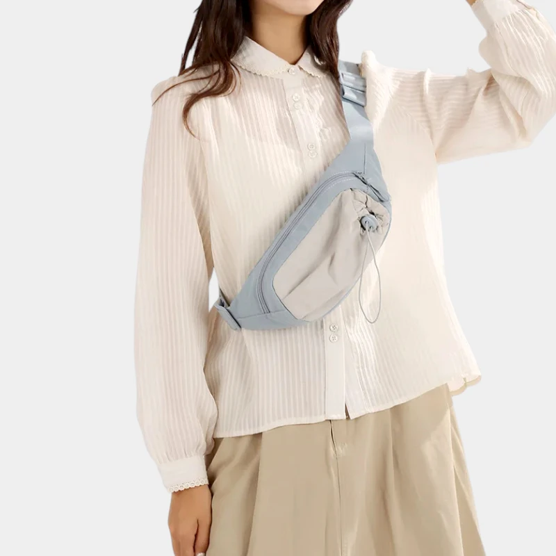 Sac banane en nylon bleu ciel porté en bandoulière sur la poitrine par une femme, de face