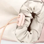 Sac Banane Randonnée Poche Gourde Nylon Déperlant Sac banane en nylon rose pâle en gros plan sur la poche beige et le stoppeur de son cordon élastique