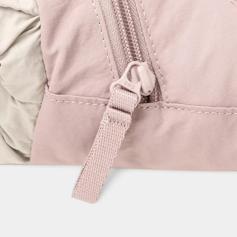 Sac banane en nylon rose pâle en gros plan sur la fermeture éclair et sa tirette en sangle tissée