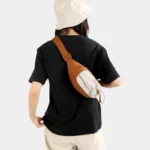 Sac Banane Randonnée Poche Gourde Nylon Déperlant Sac banane en nylon orange porté en bandoulière dans le dos par une femme avec poche avant à cordon