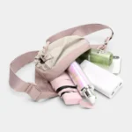 Sac Banane Randonnée Poche Gourde Nylon Déperlant Sac banane en nylon rose pâle ouvert laissant dépasser un parapluie pliant et une gourde