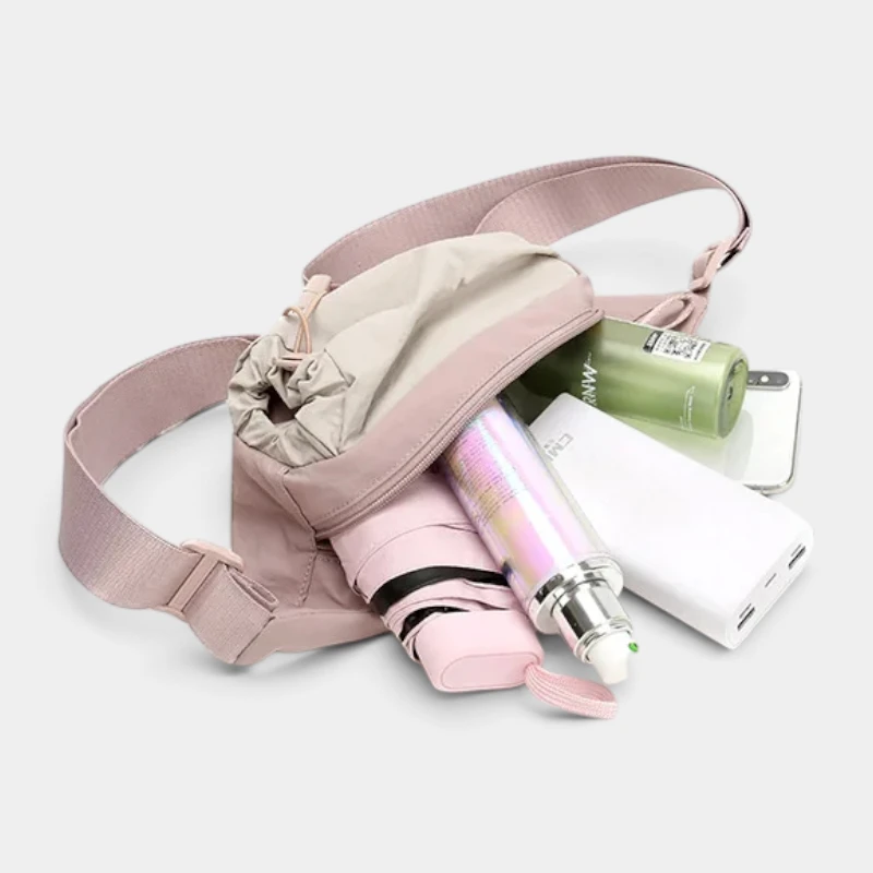 Sac banane en nylon rose pâle ouvert laissant dépasser un parapluie pliant et une gourde
