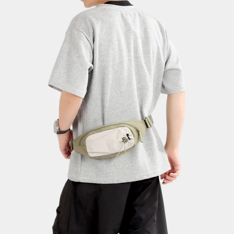 Sac banane en nylon vert kaki porté à la taille par un homme de dos avec poche avant à cordon