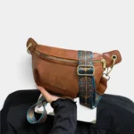 Sac banane simili cuir camel tenu à la main, avec une sangle ethnique à motif bleu et doré