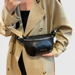 Sac banane simili cuir noir porté à la taille par une femme au style chic