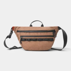 Sac banane marron cuivré en nylon ripstop à quadrillage blanc posé de face sur fond gris