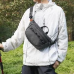 Sac banane noir porté sur la poitrine par un randonneur avec sa boucle clip sur l'épaule