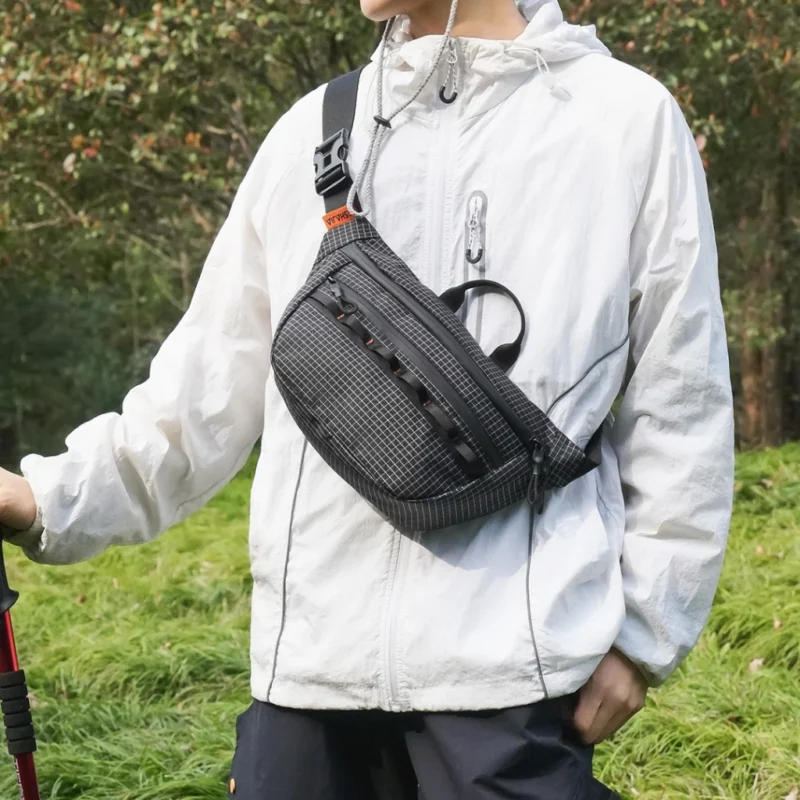 Sac banane noir porté sur la poitrine par un randonneur avec sa boucle clip sur l'épaule