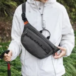 Sac banane noir en nylon ripstop porté sur la poitrine par un randonneur en plein air